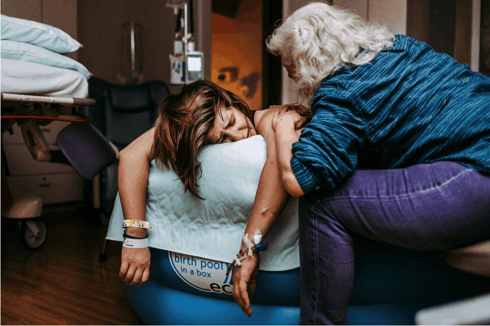 doula helping laboring mother in tub